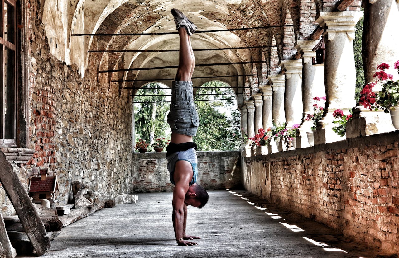 Crafting Captivating Headlines: Your awesome post title goes here A man performs a handstand in a rustic, arched corridor with brick walls and flowers.